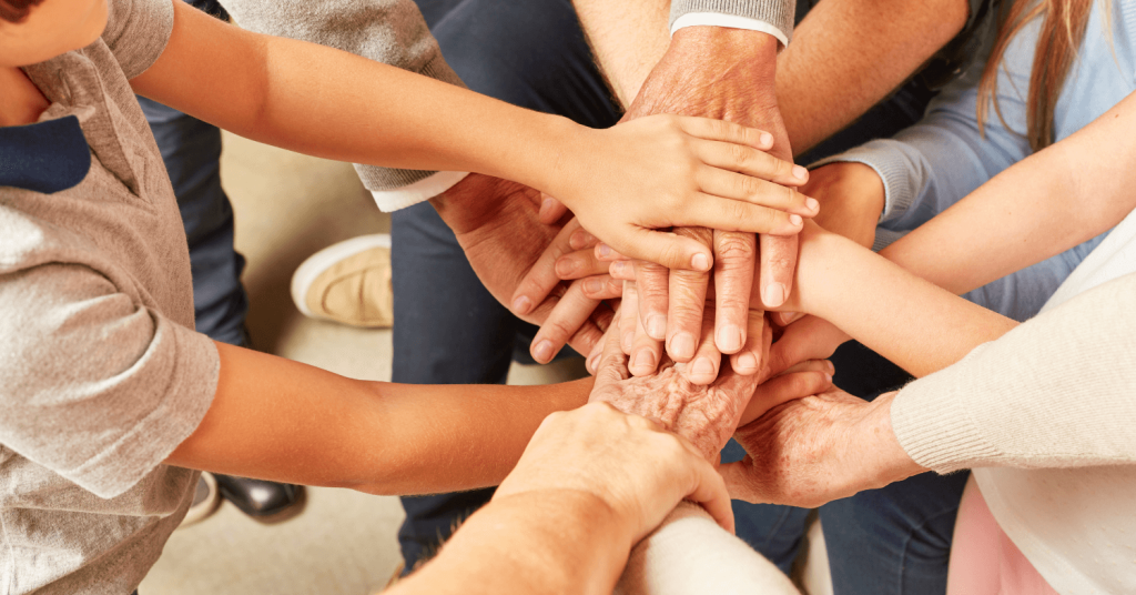 An image depicting hands from different generations, stacked on top of each other, symbolising family constellations and the connection between diverse age groups across time