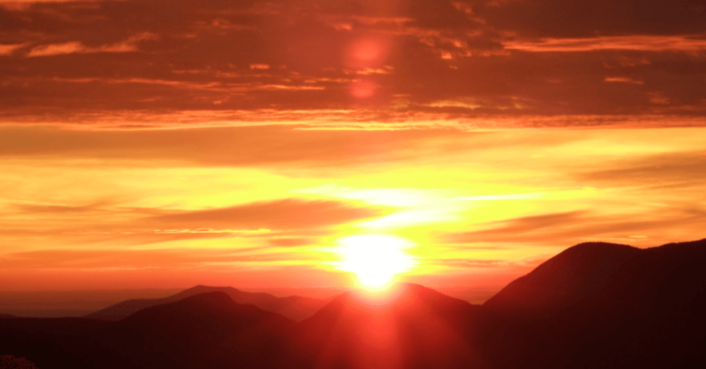 A breathtaking sunset over a mountain range, casting a golden glow across the sky.
