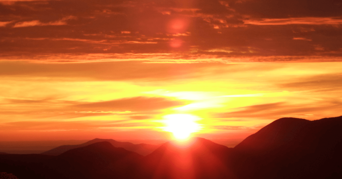 A breathtaking sunset over a mountain range, casting a golden glow across the sky.