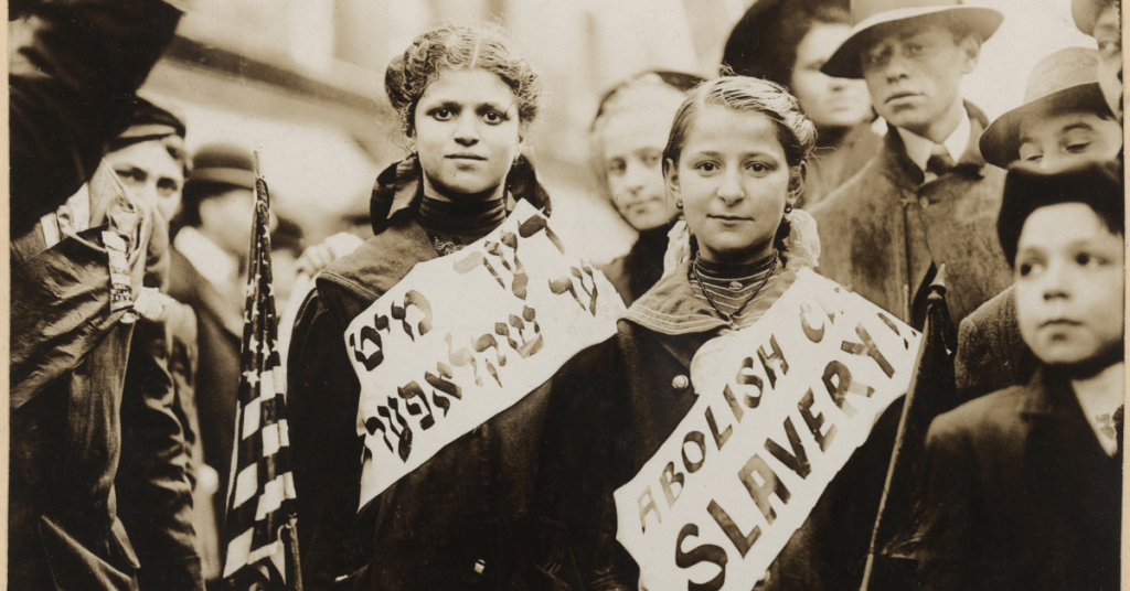 Historic black-and-white photo of two young girls wearing sashes protesting child slavery
