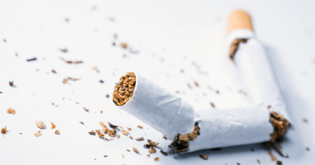 A broken cigarette lying on a white surface with loose tobacco scattered around, symbolising quitting smoking or the harmful effects of tobacco use